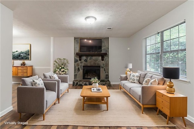5218 Tina Ct, Stone Mountain, GA 30083 - living area featuring wood finished floors, a textured ceiling, a stone fireplace, and baseboards