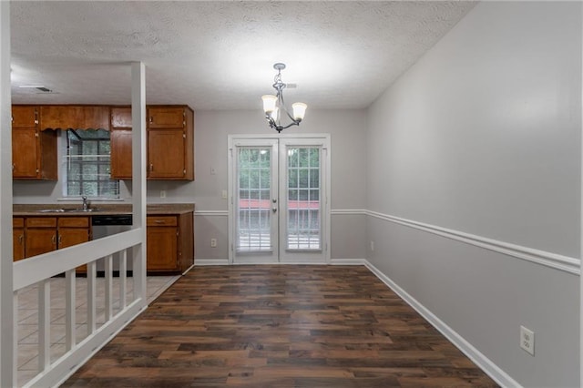 5218 Tina Ct, Stone Mountain, GA 30083 - kitchen with brown cabinets, dark wood finished floors, stainless steel dishwasher, a chandelier, and a textured ceiling