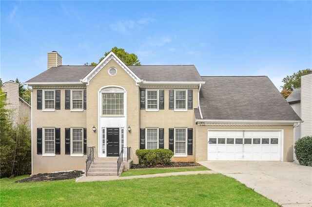 colonial inspired home featuring a garage and a front yard