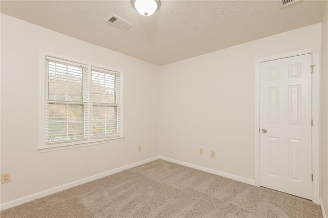 carpeted spare room with a textured ceiling
