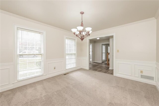 carpeted spare room featuring an inviting chandelier and crown molding