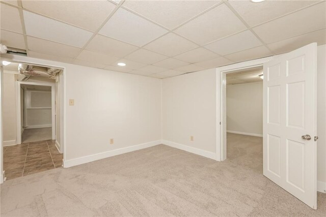 basement with light colored carpet and a paneled ceiling