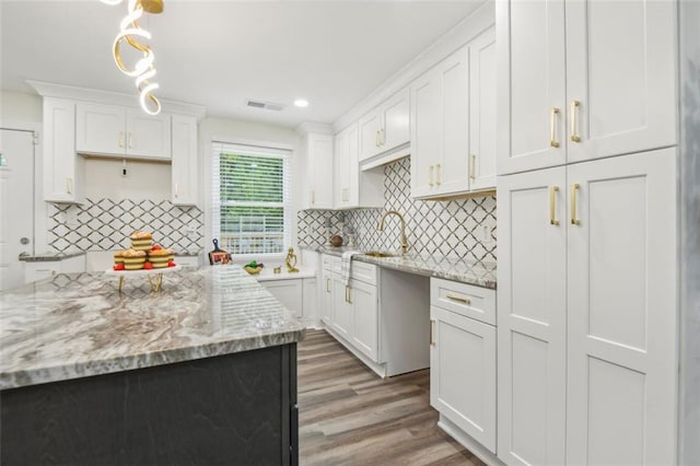 kitchen featuring decorative backsplash, hanging light fixtures, hardwood / wood-style flooring, and light stone counters