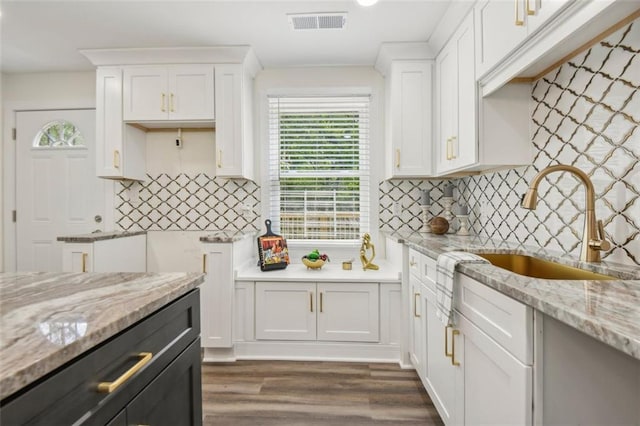 kitchen featuring white cabinets, backsplash, wood-type flooring, and light stone countertops