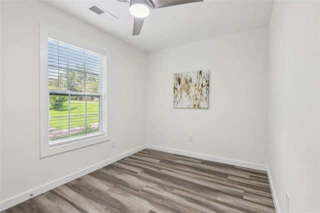 empty room featuring a healthy amount of sunlight, ceiling fan, and dark wood-type flooring