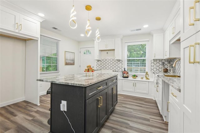 kitchen featuring decorative backsplash, hardwood / wood-style flooring, white cabinets, and decorative light fixtures