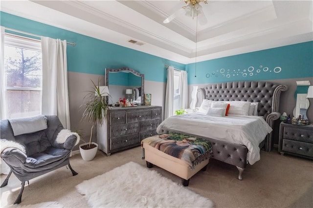 bedroom with crown molding, ceiling fan, a tray ceiling, and light carpet
