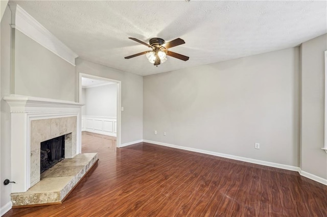 unfurnished living room featuring ceiling fan, a fireplace, dark hardwood / wood-style flooring, and a textured ceiling