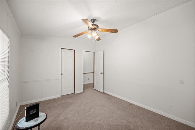 unfurnished bedroom featuring carpet floors, baseboards, and a ceiling fan