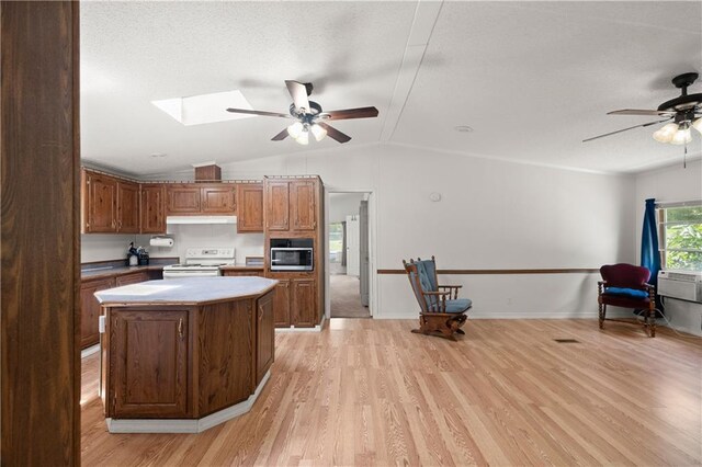 kitchen featuring white electric stove, a ceiling fan, stainless steel microwave, light wood finished floors, and lofted ceiling