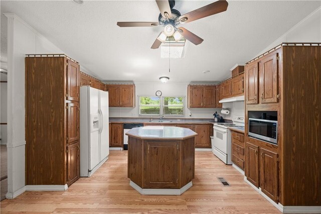 kitchen with white appliances, under cabinet range hood, light wood-style floors, a ceiling fan, and a kitchen island
