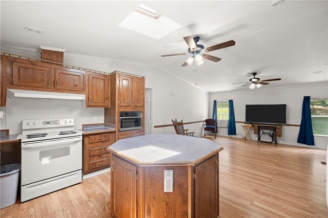 kitchen with electric stove, under cabinet range hood, stainless steel microwave, light wood-style flooring, and brown cabinetry
