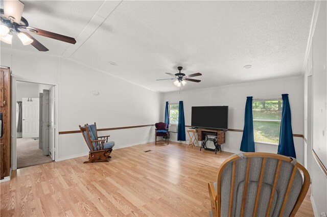 sitting room featuring ceiling fan, light wood-style floors, lofted ceiling, and a textured ceiling