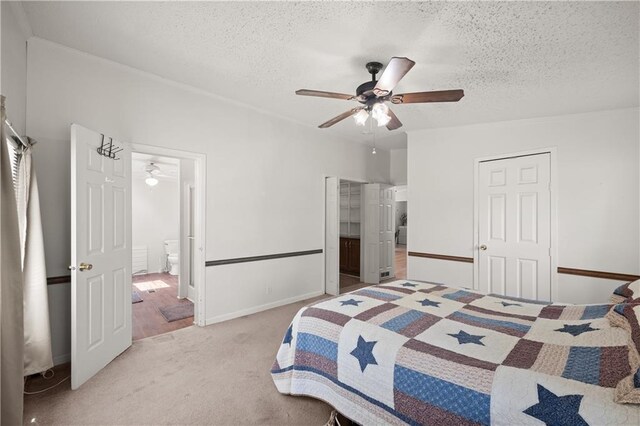bedroom with a textured ceiling, carpet floors, a ceiling fan, baseboards, and connected bathroom