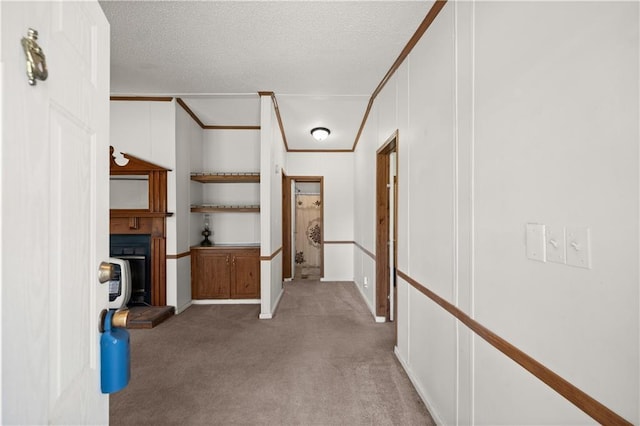 hallway with carpet floors, a textured ceiling, baseboards, and crown molding