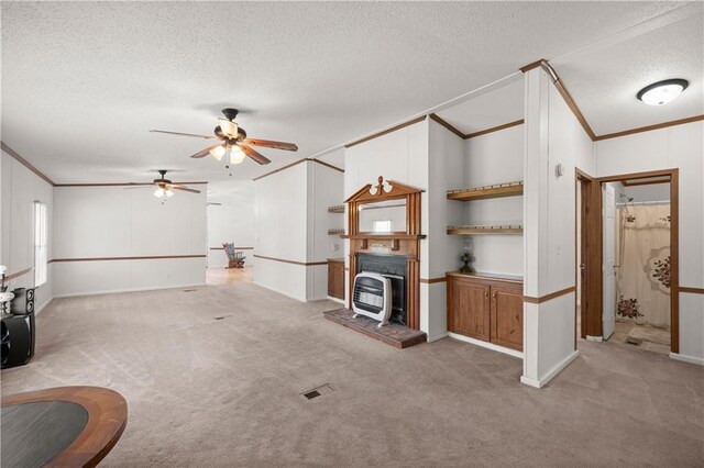 unfurnished living room with crown molding, a textured ceiling, carpet floors, and a ceiling fan