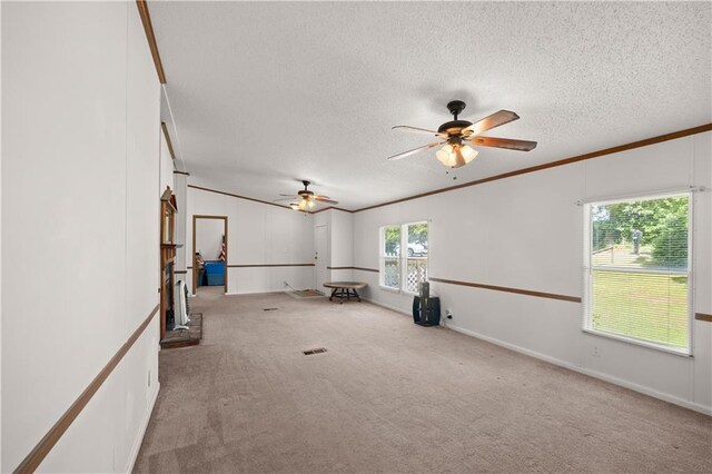 carpeted empty room featuring a ceiling fan, a textured ceiling, and ornamental molding
