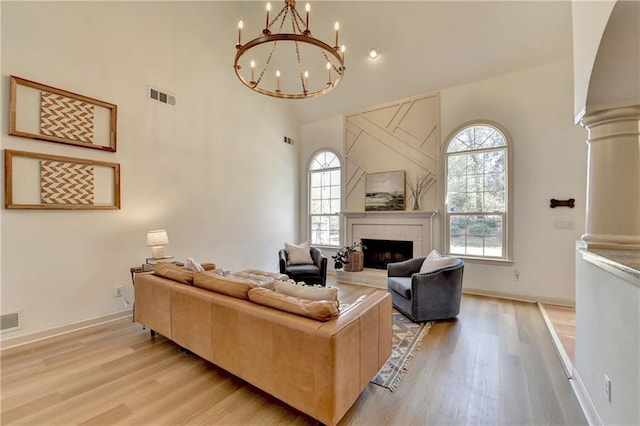 living room featuring high vaulted ceiling, plenty of natural light, visible vents, and a tiled fireplace