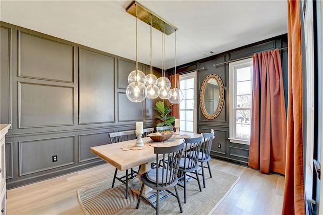 dining room with light wood-style flooring and a decorative wall