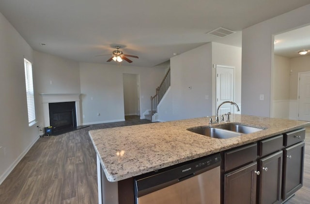 kitchen with an island with sink, sink, dark hardwood / wood-style flooring, stainless steel dishwasher, and dark brown cabinetry