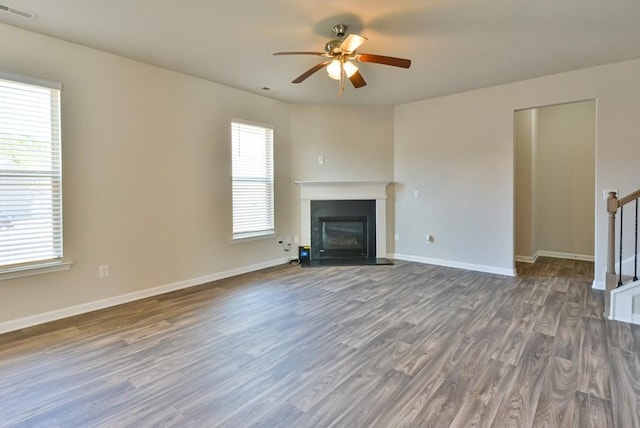 unfurnished living room featuring dark wood-type flooring and ceiling fan