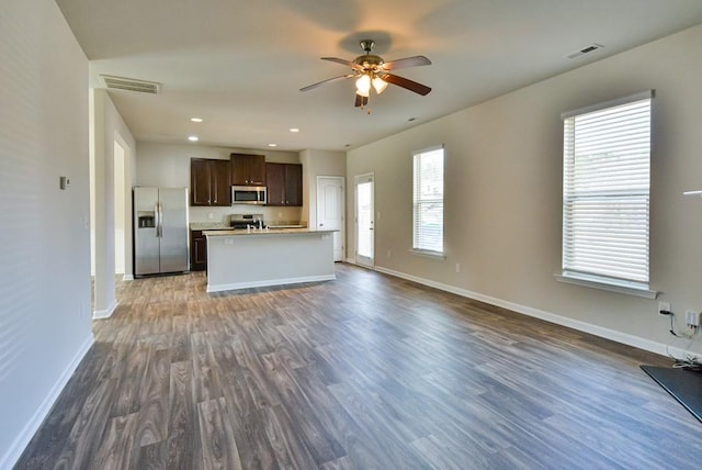 kitchen featuring dark hardwood / wood-style flooring, a kitchen island with sink, ceiling fan, stainless steel appliances, and dark brown cabinets