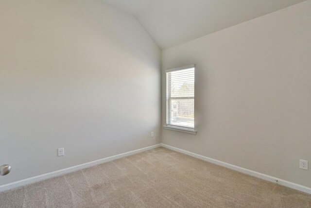 spare room with lofted ceiling and light colored carpet