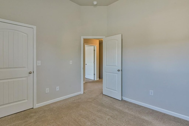 unfurnished bedroom with a towering ceiling and light carpet