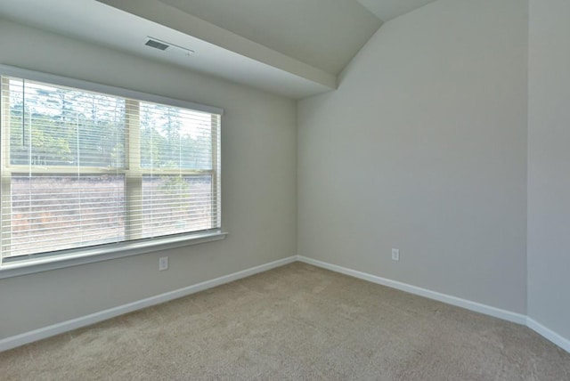 carpeted empty room featuring vaulted ceiling