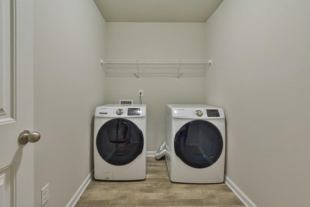 clothes washing area with separate washer and dryer and light hardwood / wood-style floors