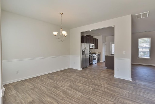 unfurnished room with an inviting chandelier and hardwood / wood-style floors