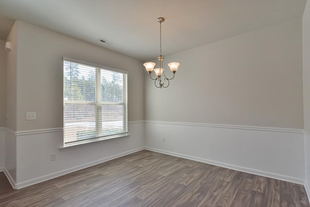 empty room with an inviting chandelier and dark hardwood / wood-style flooring