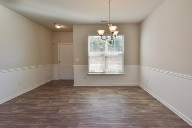 unfurnished dining area featuring dark wood-type flooring and a chandelier