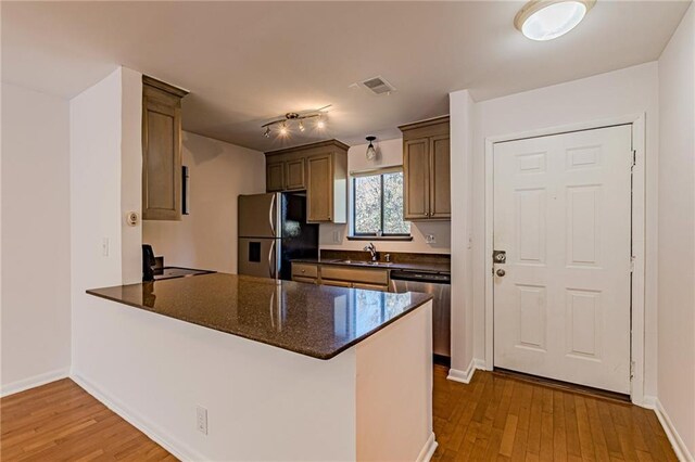 kitchen featuring appliances with stainless steel finishes, sink, kitchen peninsula, and light hardwood / wood-style floors