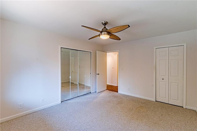 unfurnished bedroom featuring multiple closets, ceiling fan, and light carpet