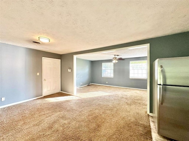 interior space with carpet flooring, a textured ceiling, and ceiling fan