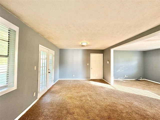 spare room with french doors, a textured ceiling, and carpet flooring