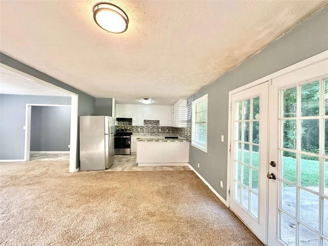 kitchen featuring appliances with stainless steel finishes, a textured ceiling, white cabinets, light colored carpet, and french doors