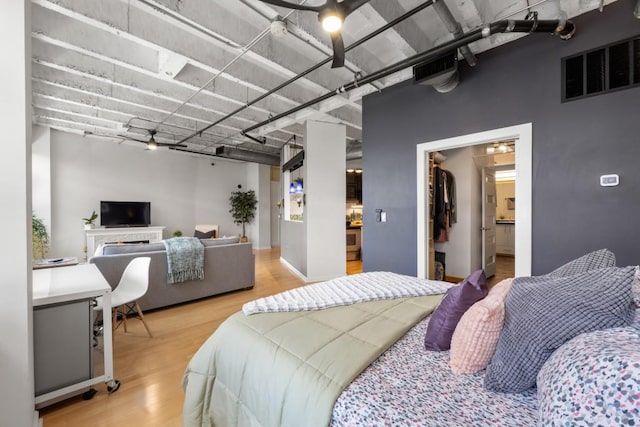 bedroom with a spacious closet and light hardwood / wood-style flooring