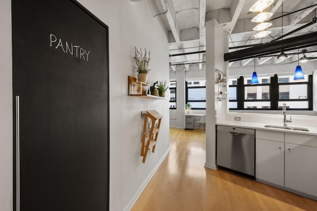 kitchen with stainless steel dishwasher, light hardwood / wood-style floors, sink, and white cabinets