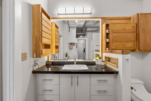 kitchen featuring sink, dark stone countertops, and white cabinets