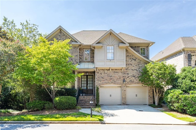 view of front facade featuring french doors, concrete driveway, an attached garage, a shingled roof, and brick siding