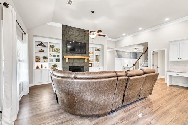 2980 Beards Rd, Buford, GA 30518 - living area featuring a stone fireplace, a ceiling fan, stairway, ornamental molding, and light wood-type flooring