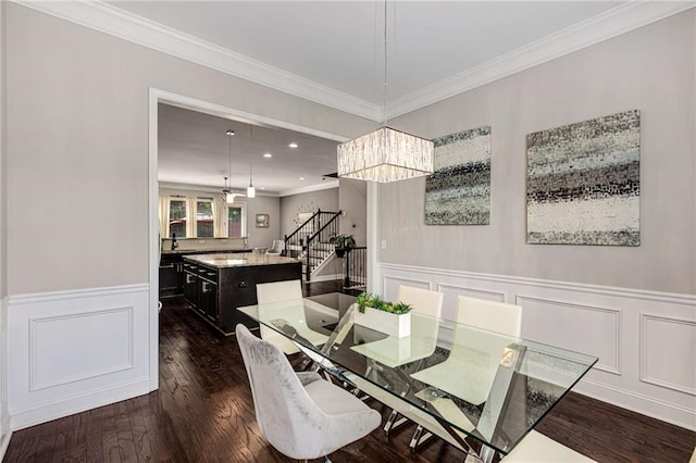 dining area featuring ornamental molding, stairs, a wainscoted wall, dark wood finished floors, and a notable chandelier