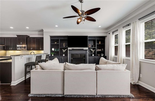 living room featuring crown molding, a fireplace, a ceiling fan, and recessed lighting