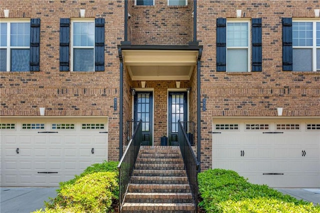 property entrance with an attached garage, driveway, and brick siding
