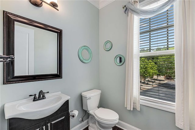 bathroom featuring baseboards, ornamental molding, toilet, and vanity