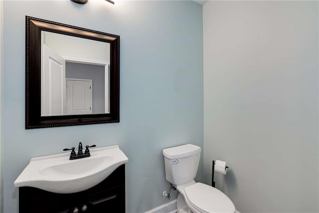 bathroom featuring baseboards, toilet, and vanity