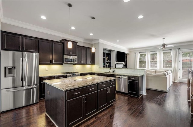 kitchen featuring a peninsula, light stone countertops, ceiling fan, a sink, and appliances with stainless steel finishes
