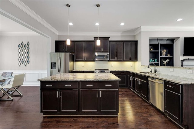 kitchen featuring hanging light fixtures, appliances with stainless steel finishes, a sink, light stone counters, and a peninsula